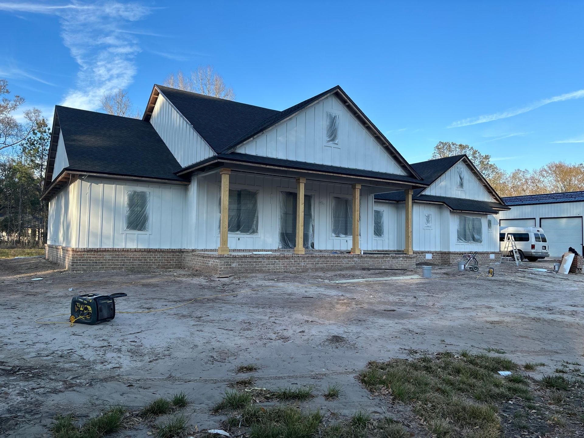 Painter on a scaffold painting exterior trim white, sunny day, residential setting.