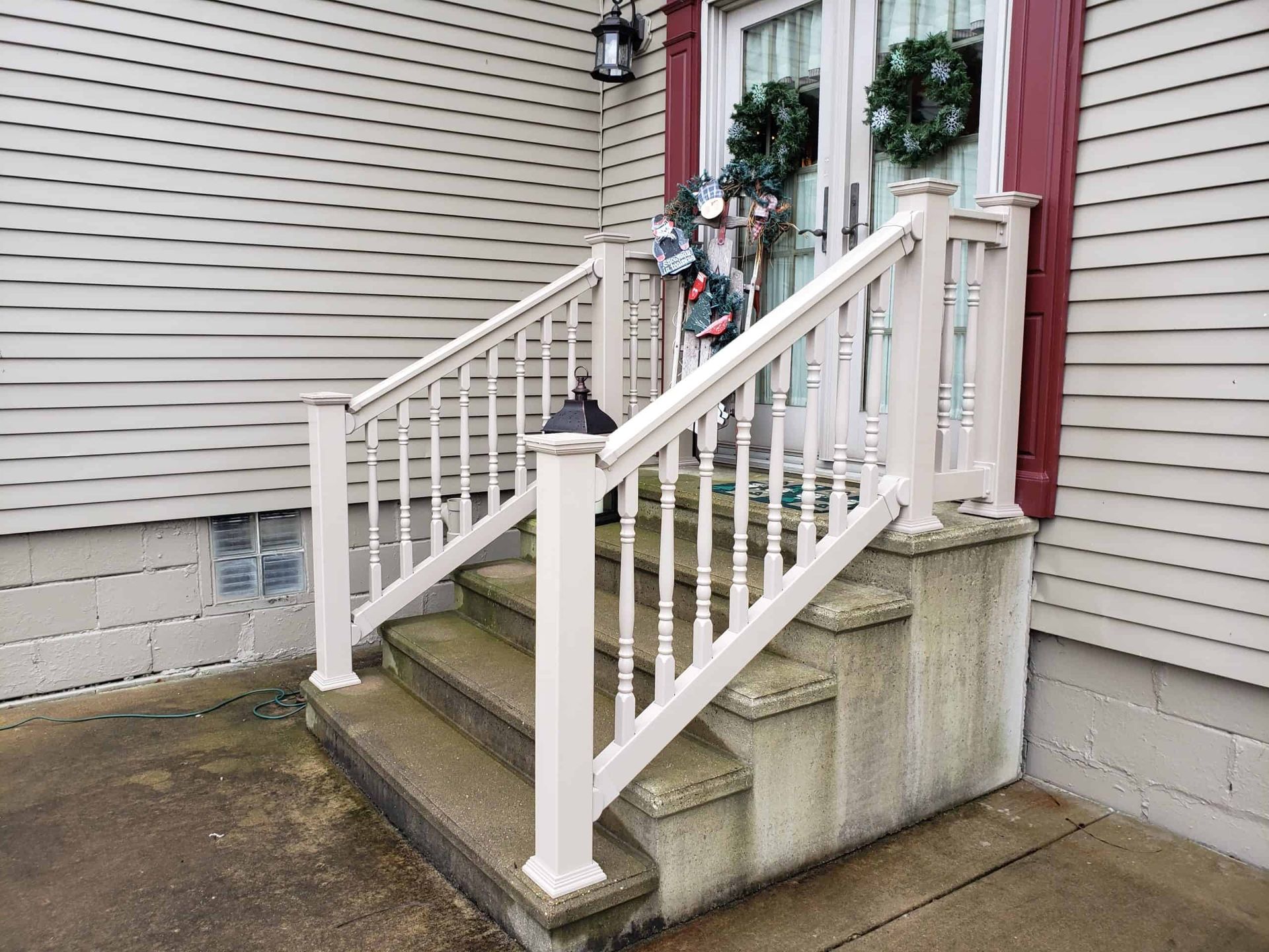 Short concrete staircase with white railing leading to a house entrance, with a scooter parked by the door