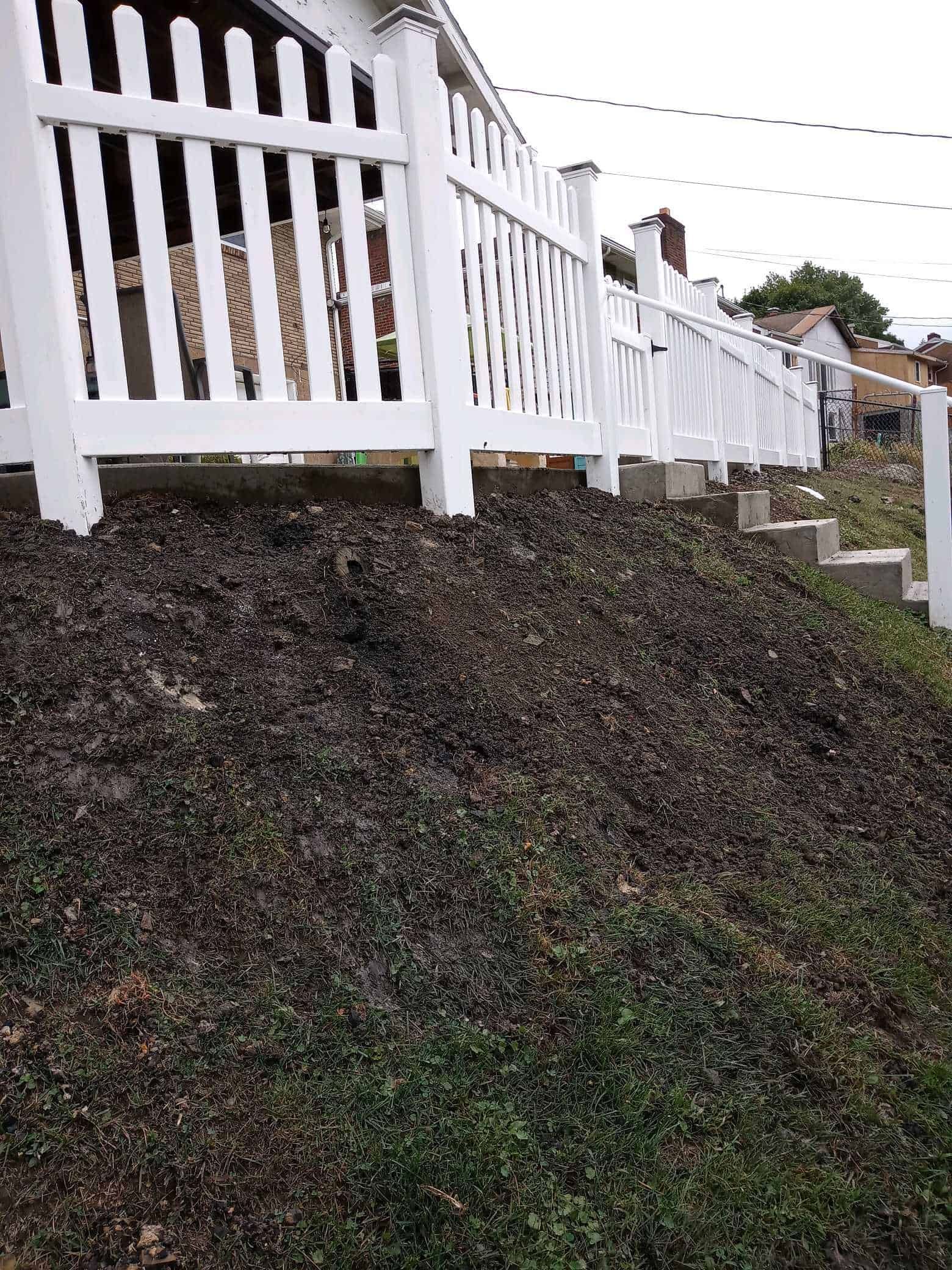 White picket fence along a steep, ivy-covered embankment beside a walkway