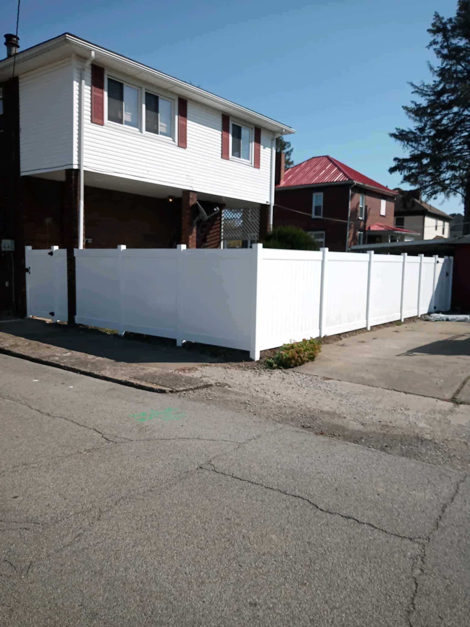 Residential house with white fence at a street corner on a sunny day