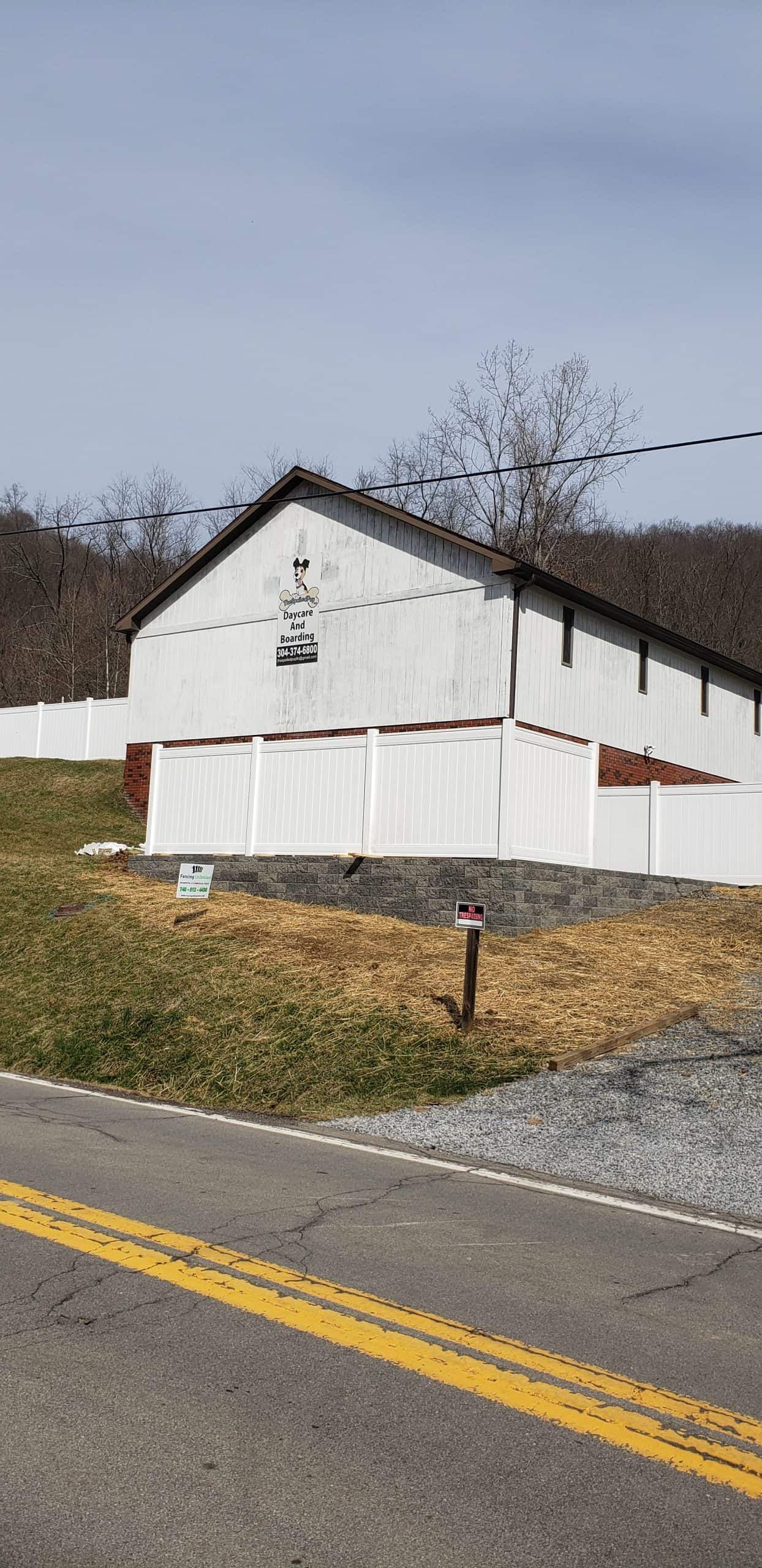 White barn-like building on a grassy roadside embankment beside a yellow-lined road