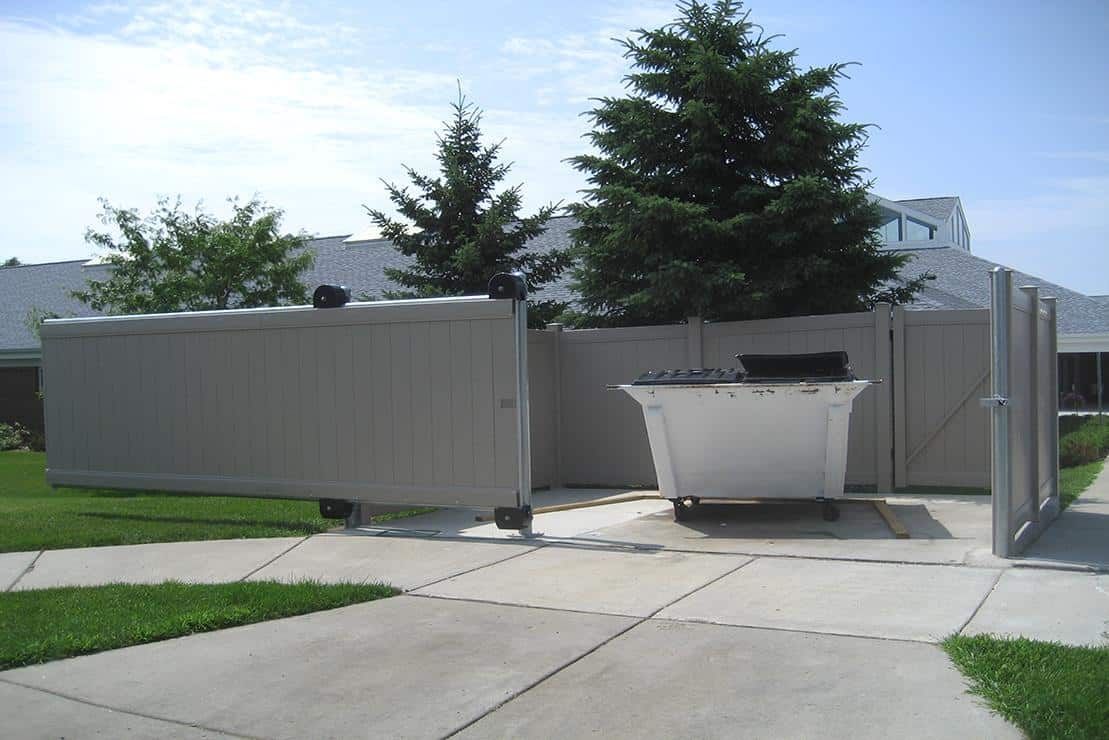 Modern outdoor patio with metal privacy screens, a large planter, and conifer trees under a clear sky
