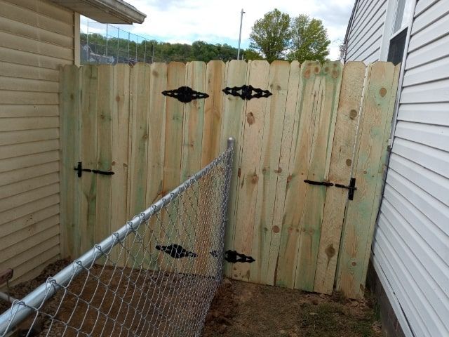 Chain-link fence leading to a newly built wooden gate between two houses in a narrow side yard