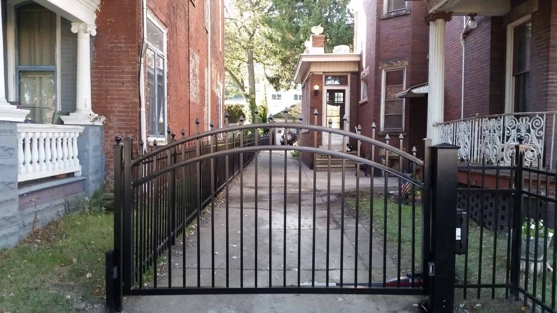 Black metal gate blocking a narrow brick alley between buildings
