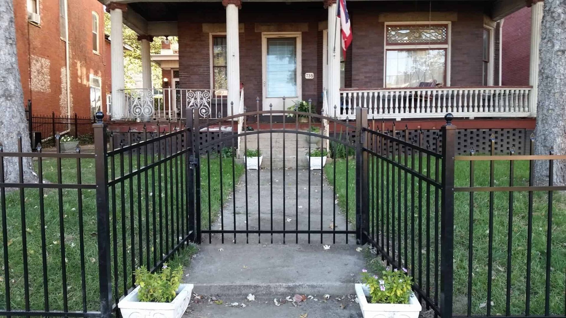 Front walkway to a brick house with black metal railings and a small porch