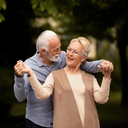 Two people smiling and dancing outdoors in soft light