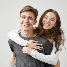 Smiling couple embracing against a light gray background