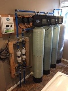 Water filtration system with multiple tanks and control panel, indoors.