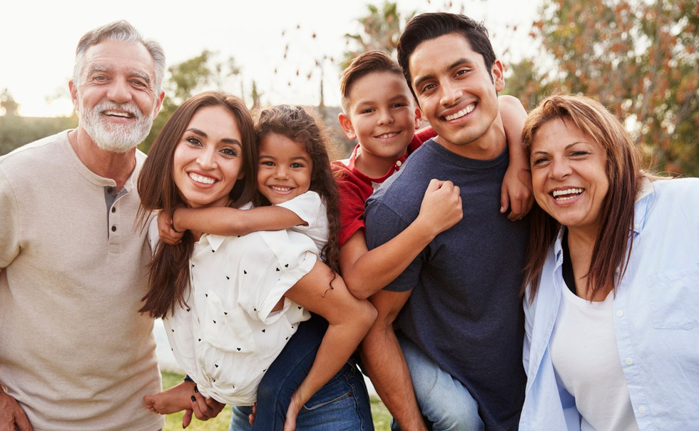 Smiling family hugging outdoors in warm sunlight at the beach