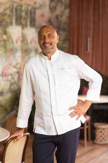 Un chef en veste blanche, la main sur la hanche, dans un restaurant.