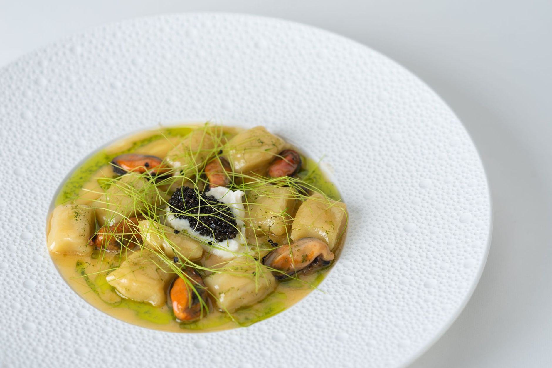 Gros plan sur un plat gastronomique. Gnocchis de pommes de terre aux moules, caviar et huile aux herbes.