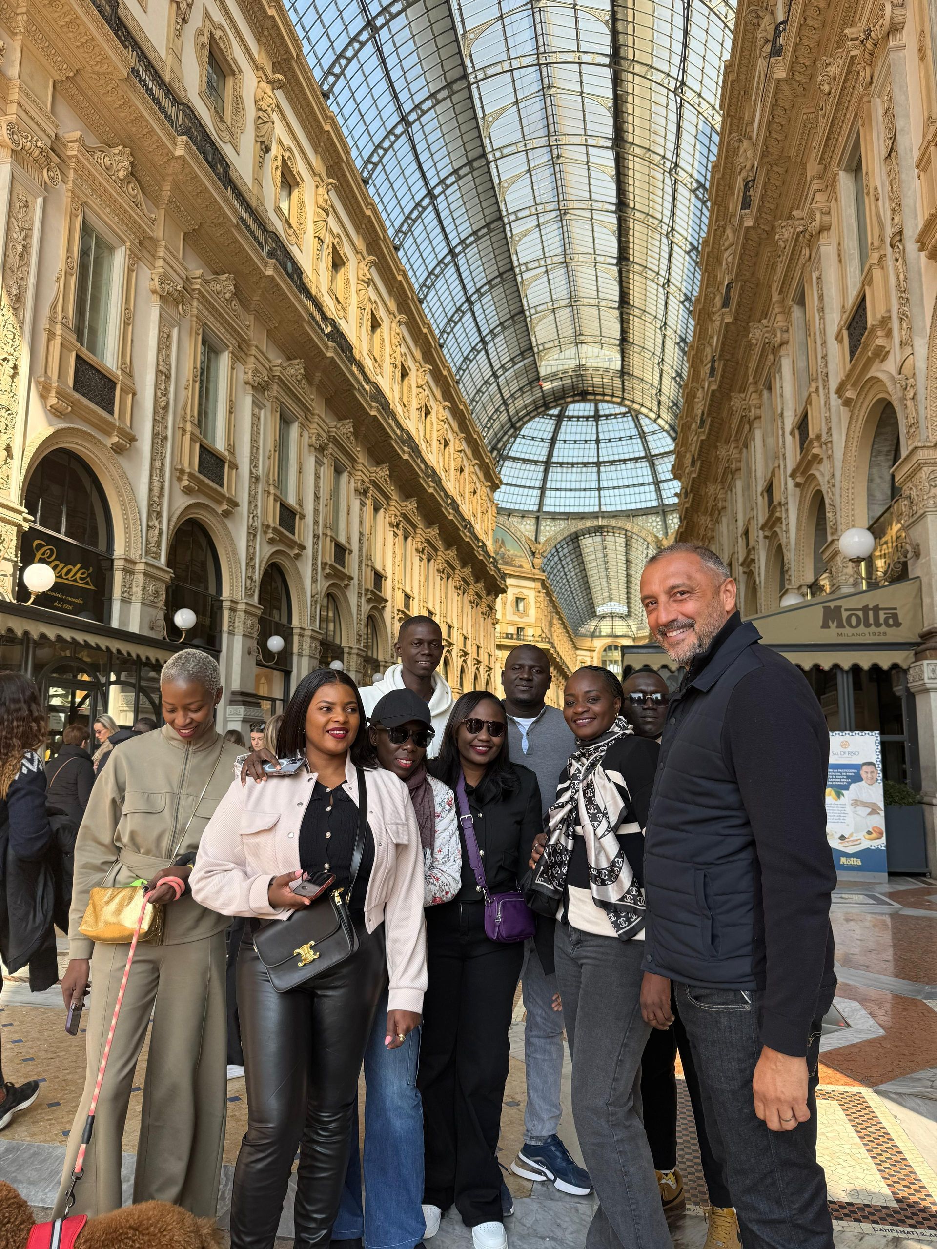 Groupe de personnes posant à l'intérieur d'une grande galerie marchande voûtée avec un plafond en verre.