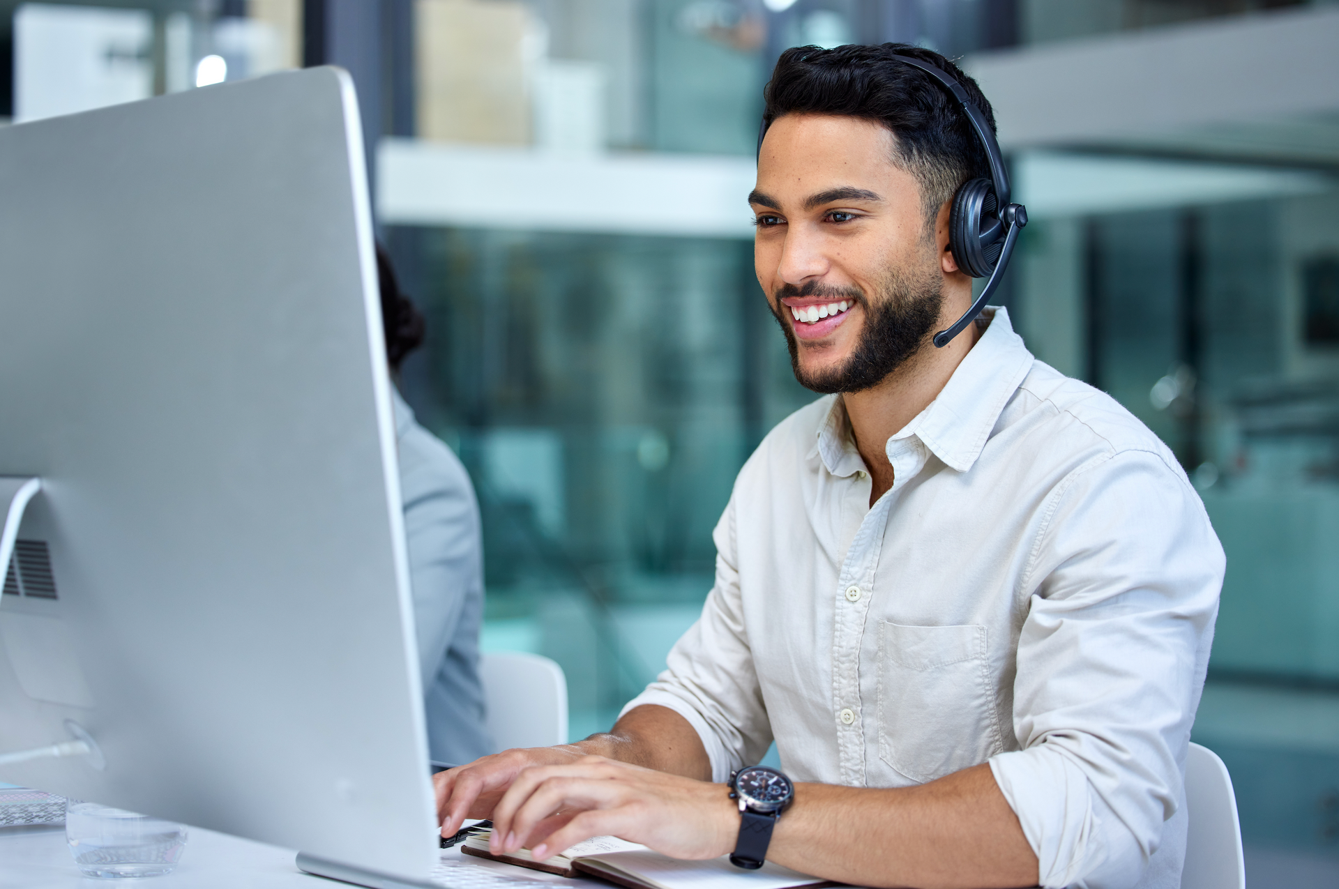 A man wearing a headset is sitting in front of a computer.