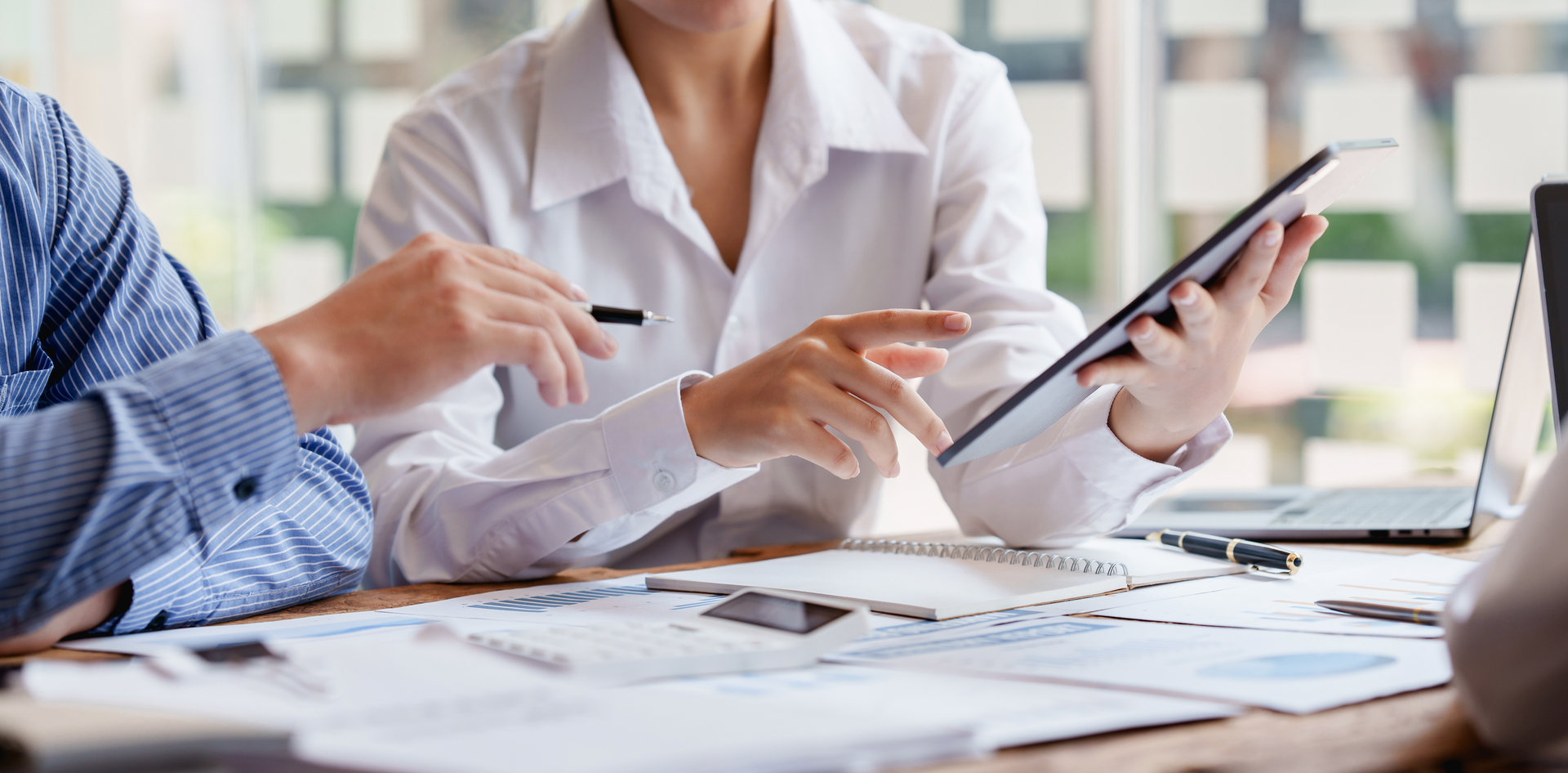 A group of people are sitting at a table looking at a tablet.