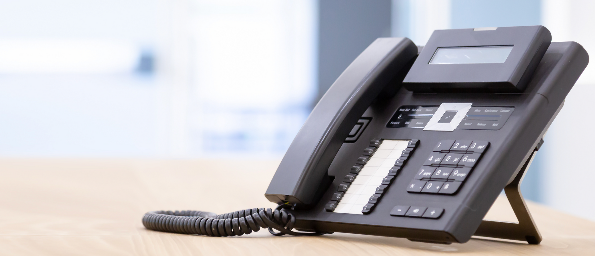 A black telephone is sitting on a wooden table.