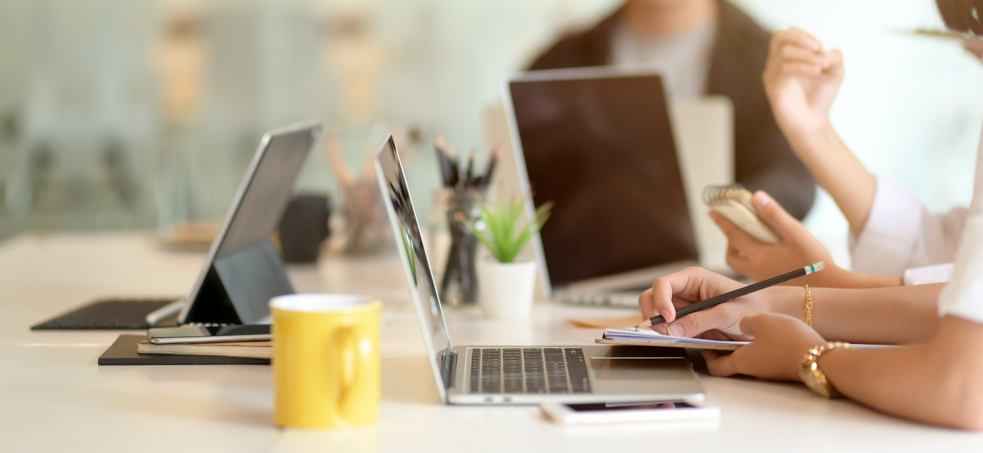 A group of people are sitting at a table with laptops.