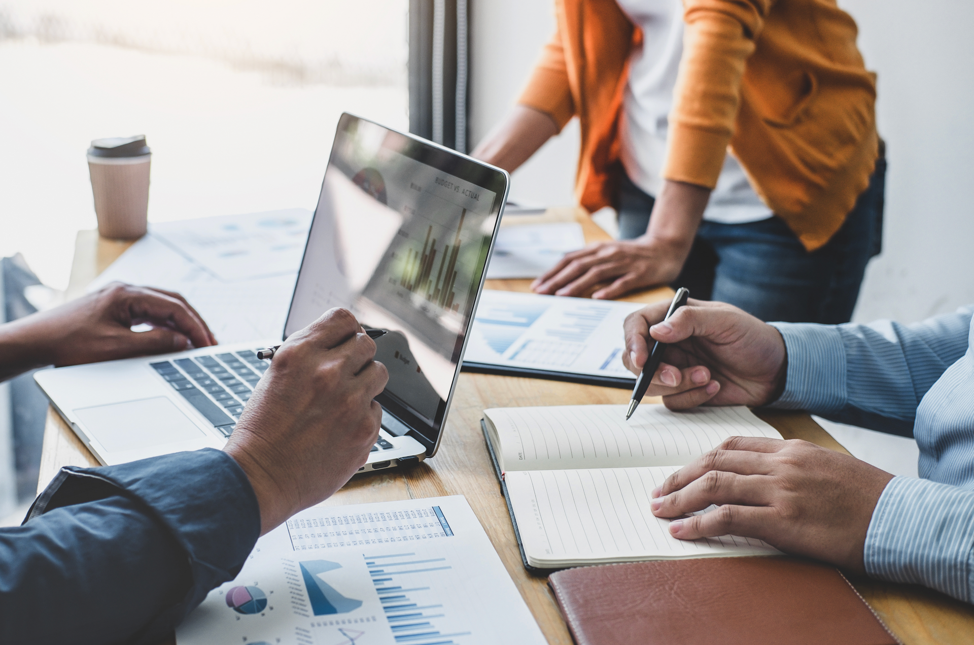 A group of people are sitting at a table with laptops and notebooks.