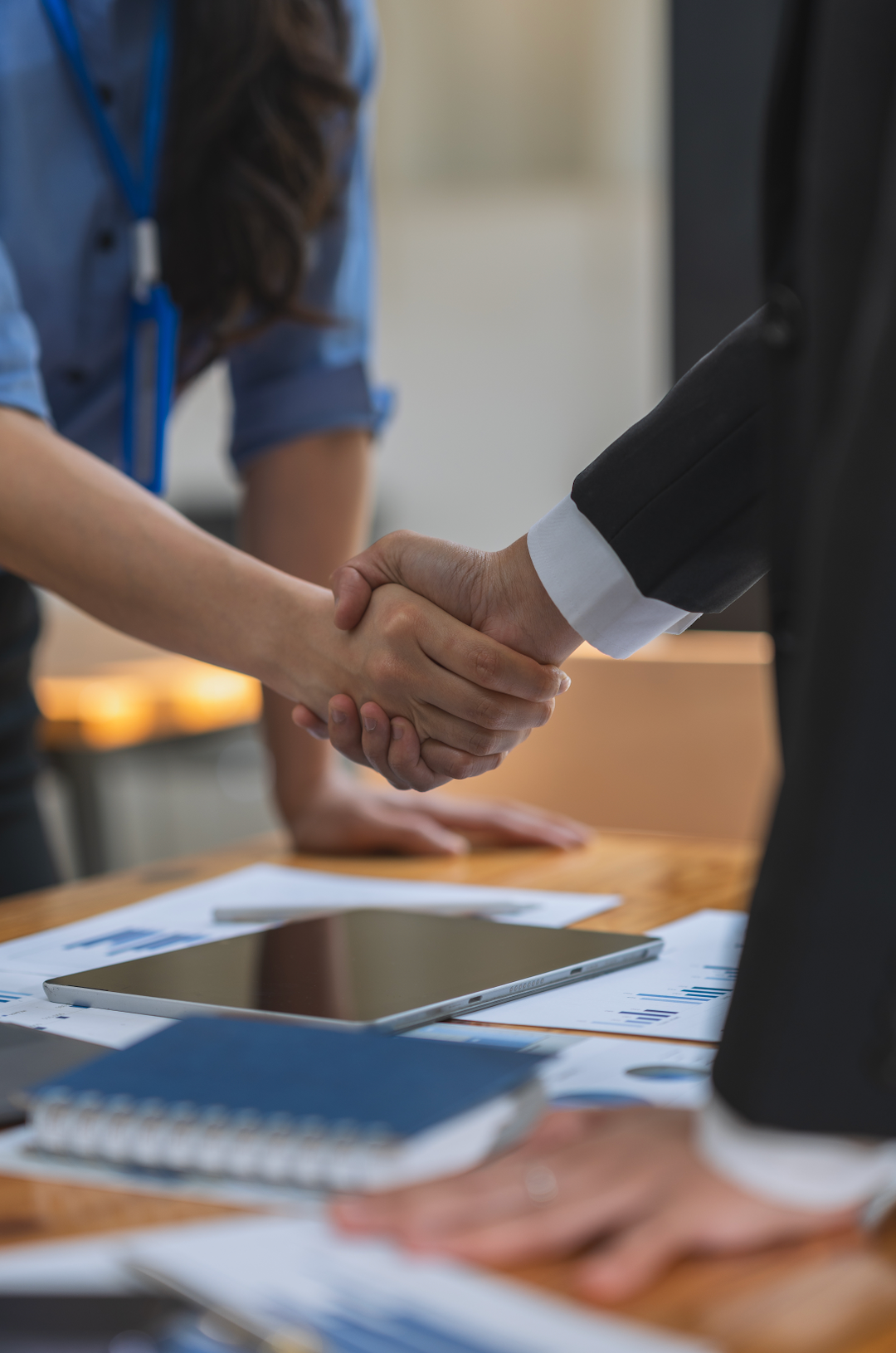 A man and a woman are shaking hands over a table.