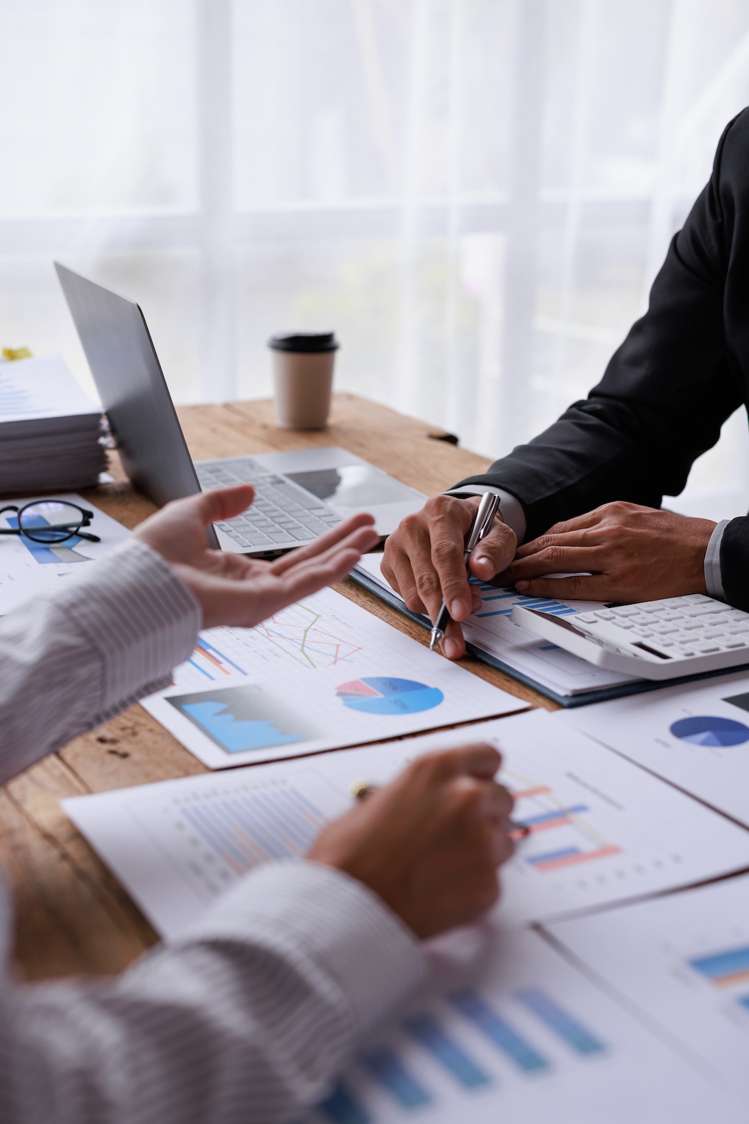 A group of people are sitting at a table with papers and a laptop.