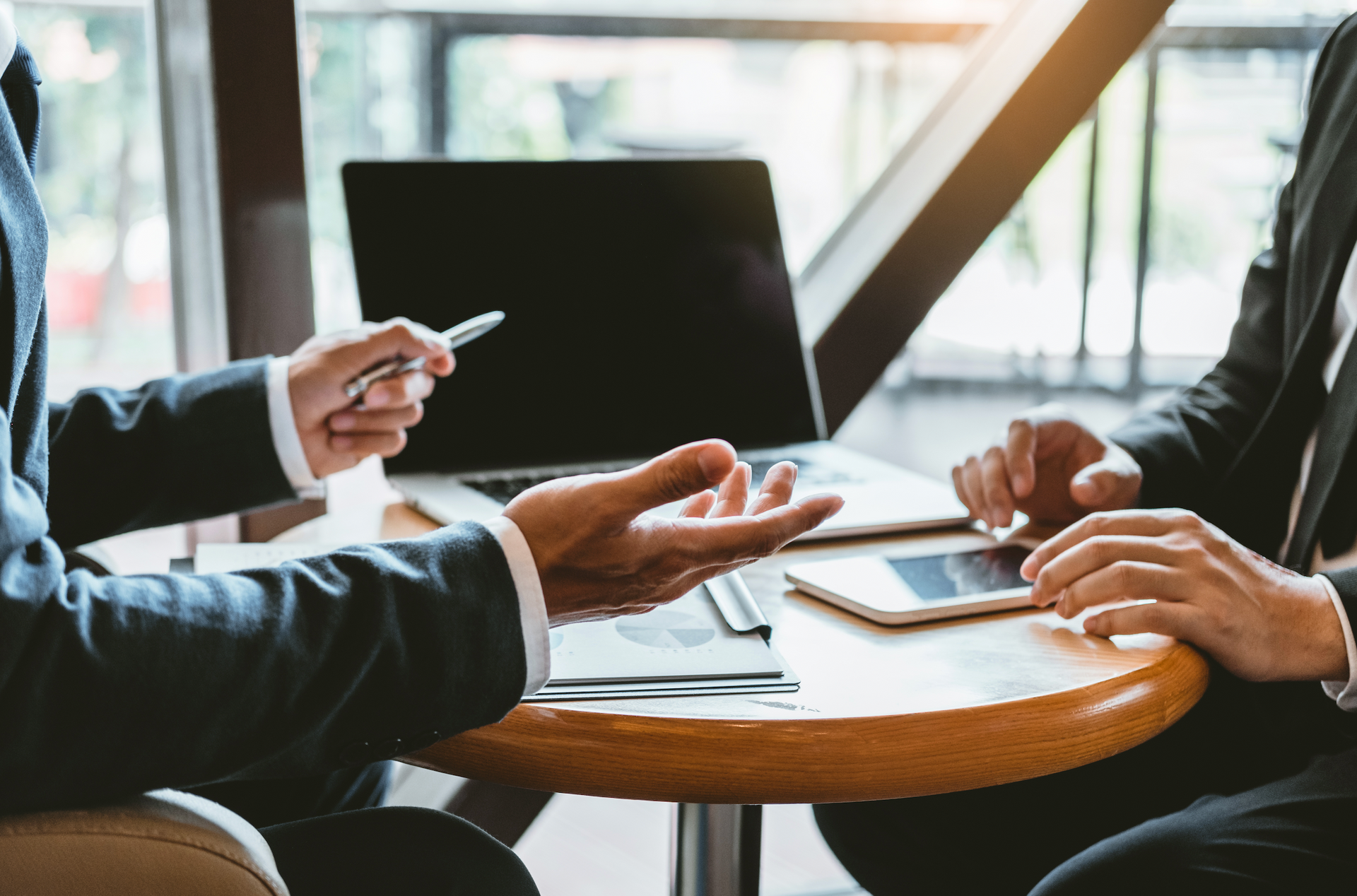 Two business people are sitting at a table with a laptop and a tablet.