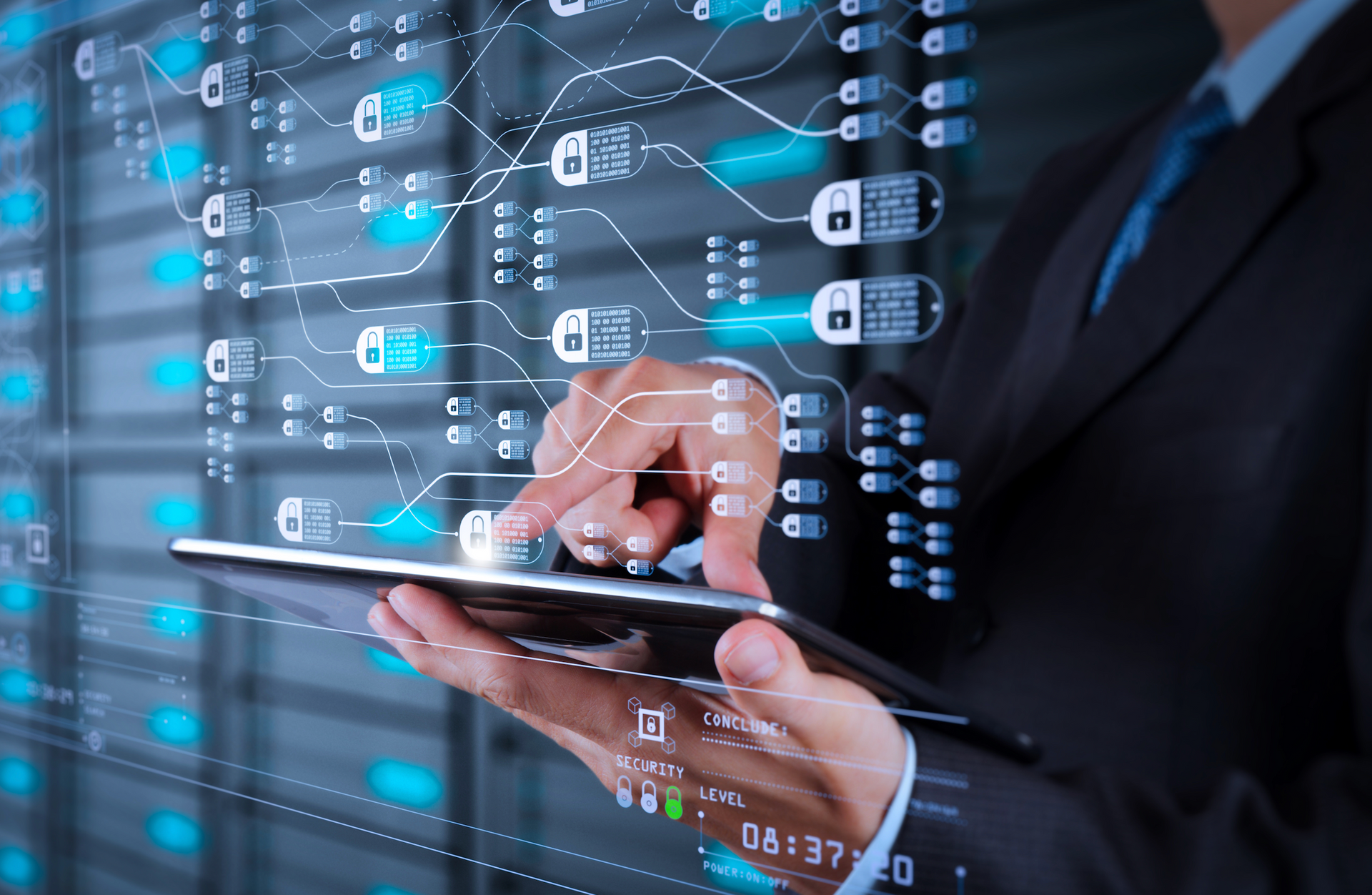 A man in a suit is using a tablet computer in a server room.
