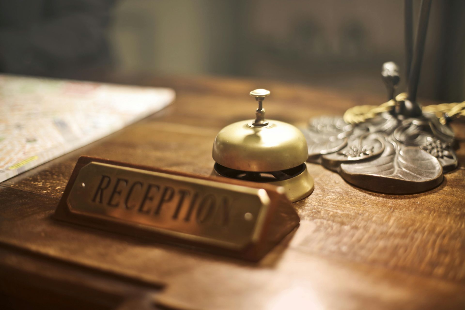 A reception bell is sitting on a wooden table next to a reception sign.
