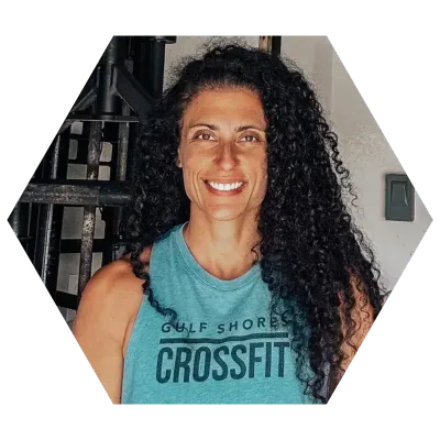 Woman with curly hair in a blue tank top smiles at the camera,