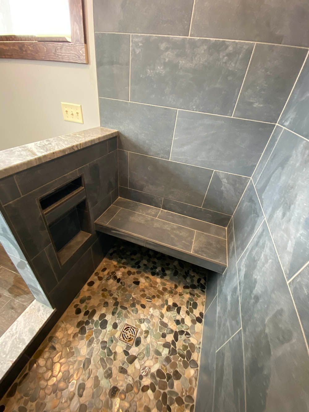 A shower with a bench in it and a window.