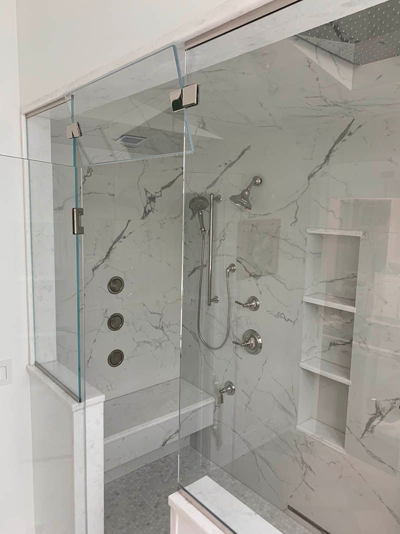 A bathroom with a glass shower door and marble walls.