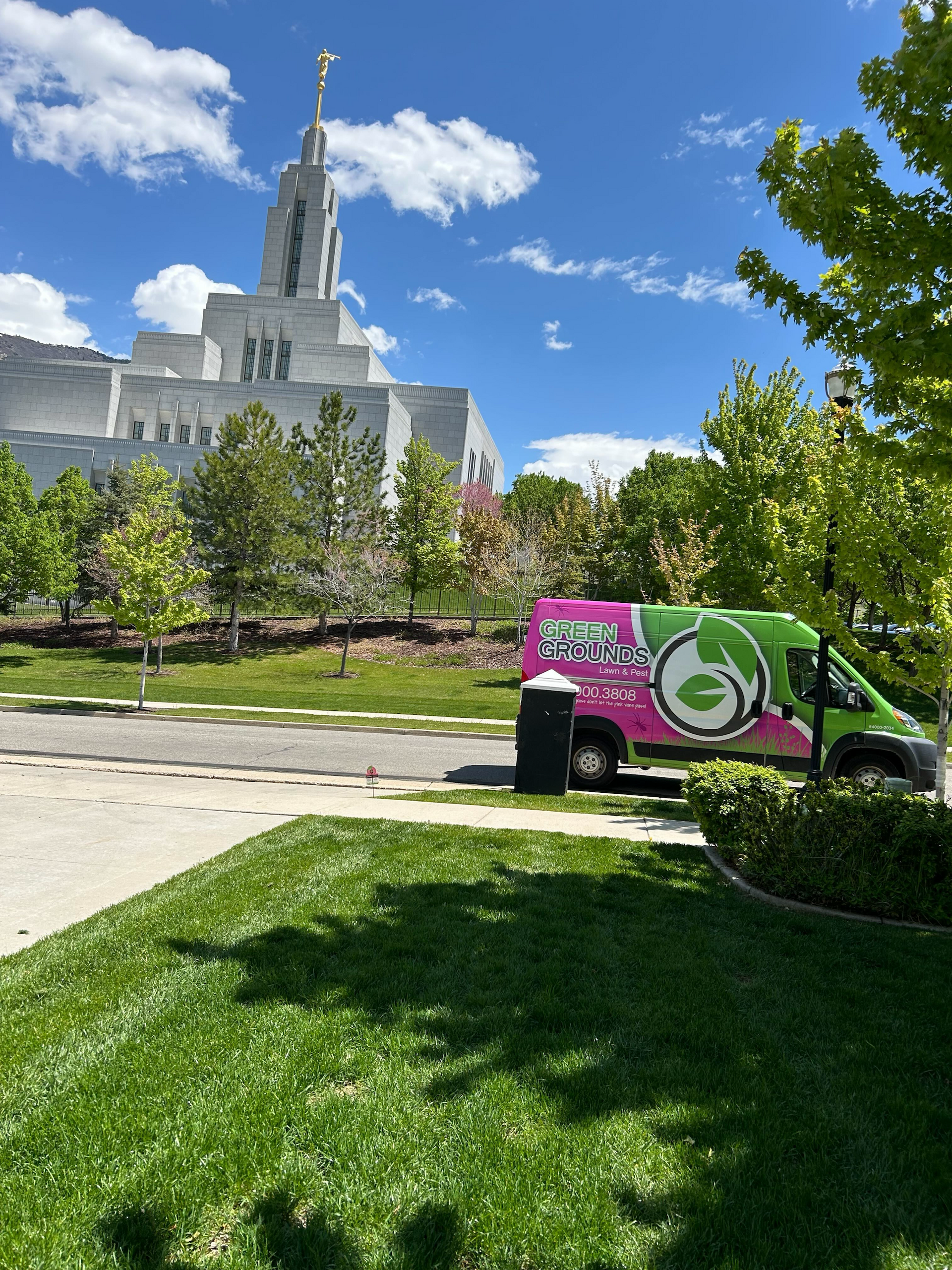 A pink and green van is parked in front of a temple.