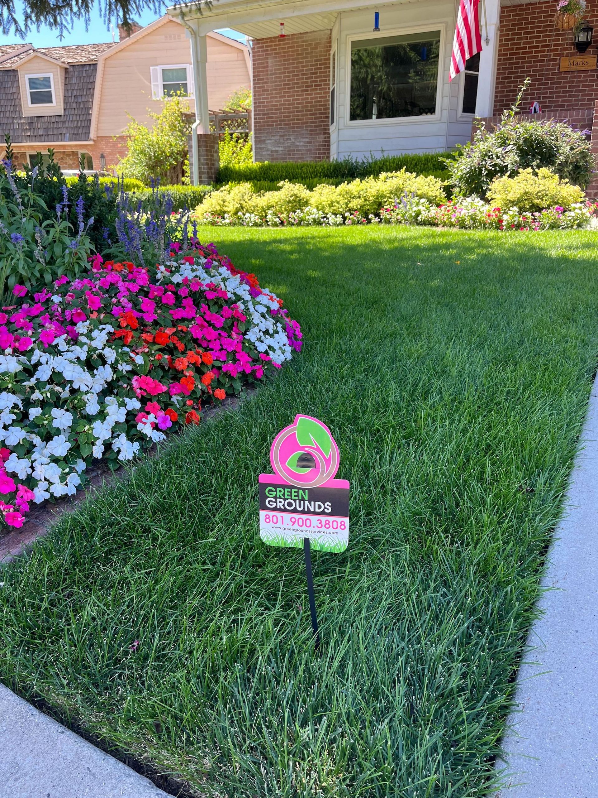 A house with a lush green lawn and flowers in front of it.