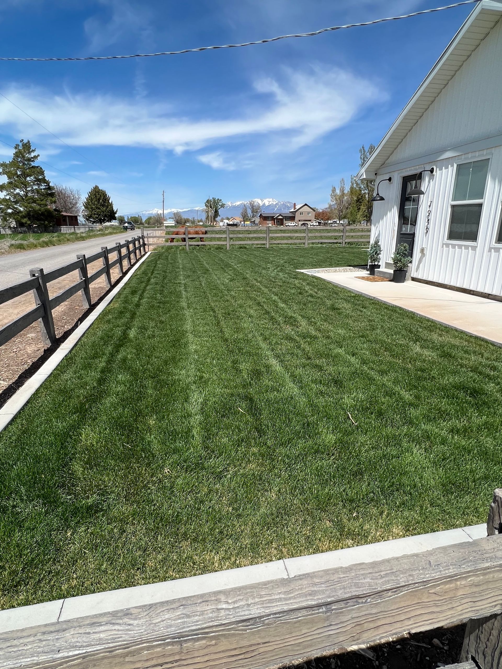 A white house with a fence and a lush green lawn in front of it.
