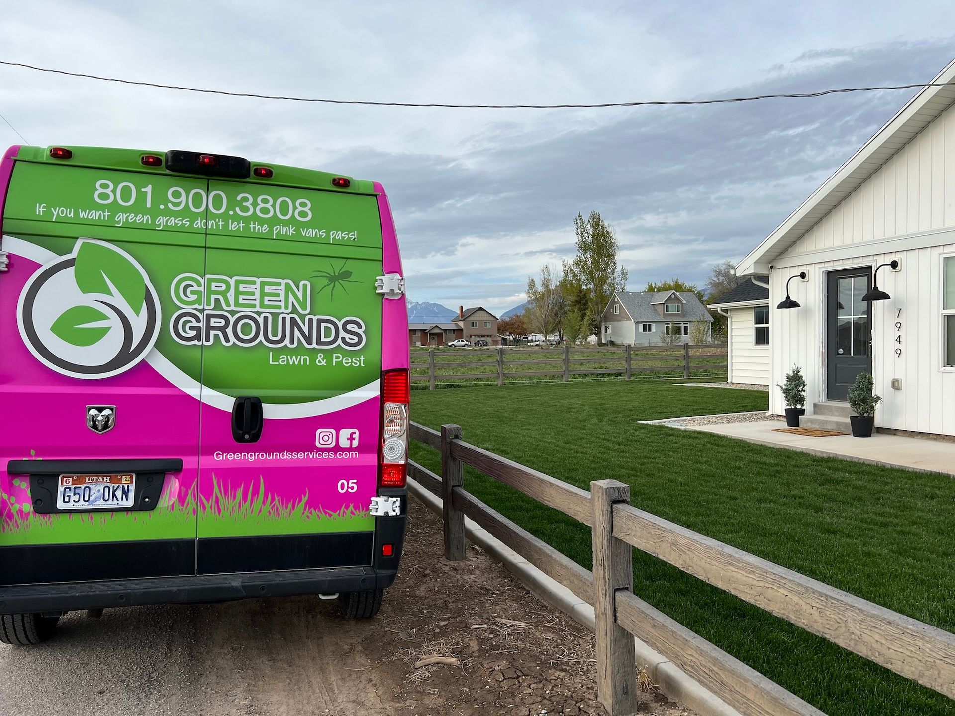A pink and green van is parked in front of a house.