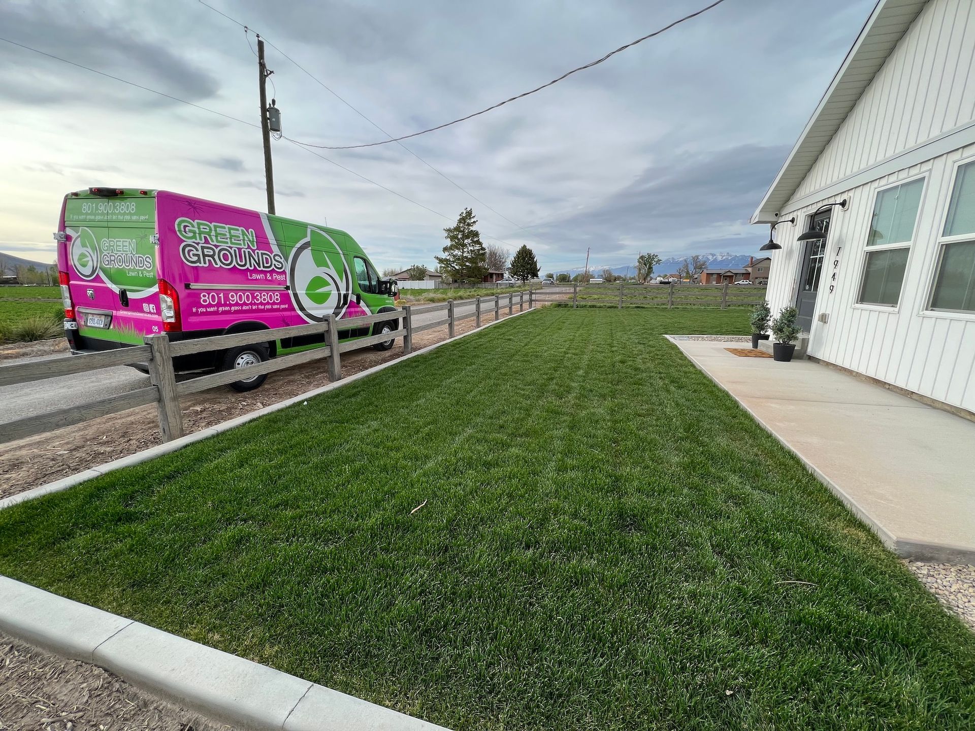 A pink and green van is parked in front of a house.