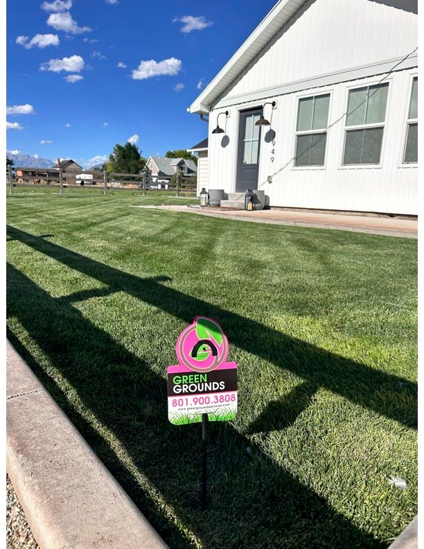 A house with a lush green lawn and a sign in front of it.