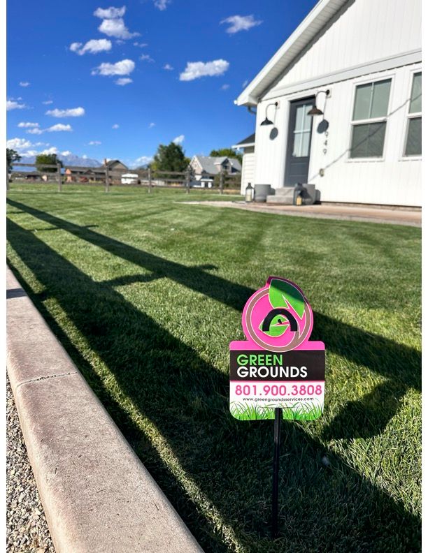 A sign for green grounds is in front of a house.