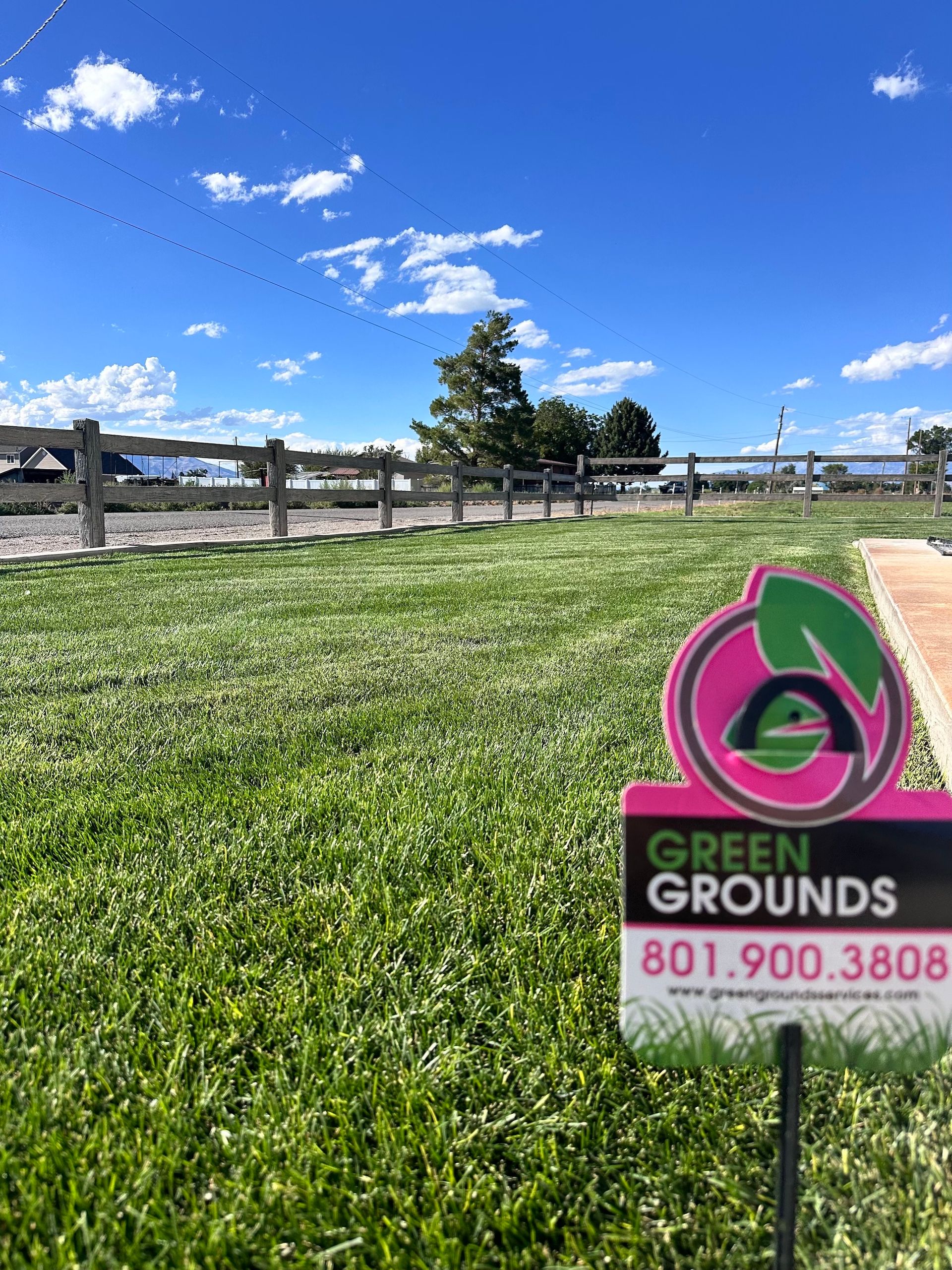 A sign for green grounds is in the middle of a lush green field.