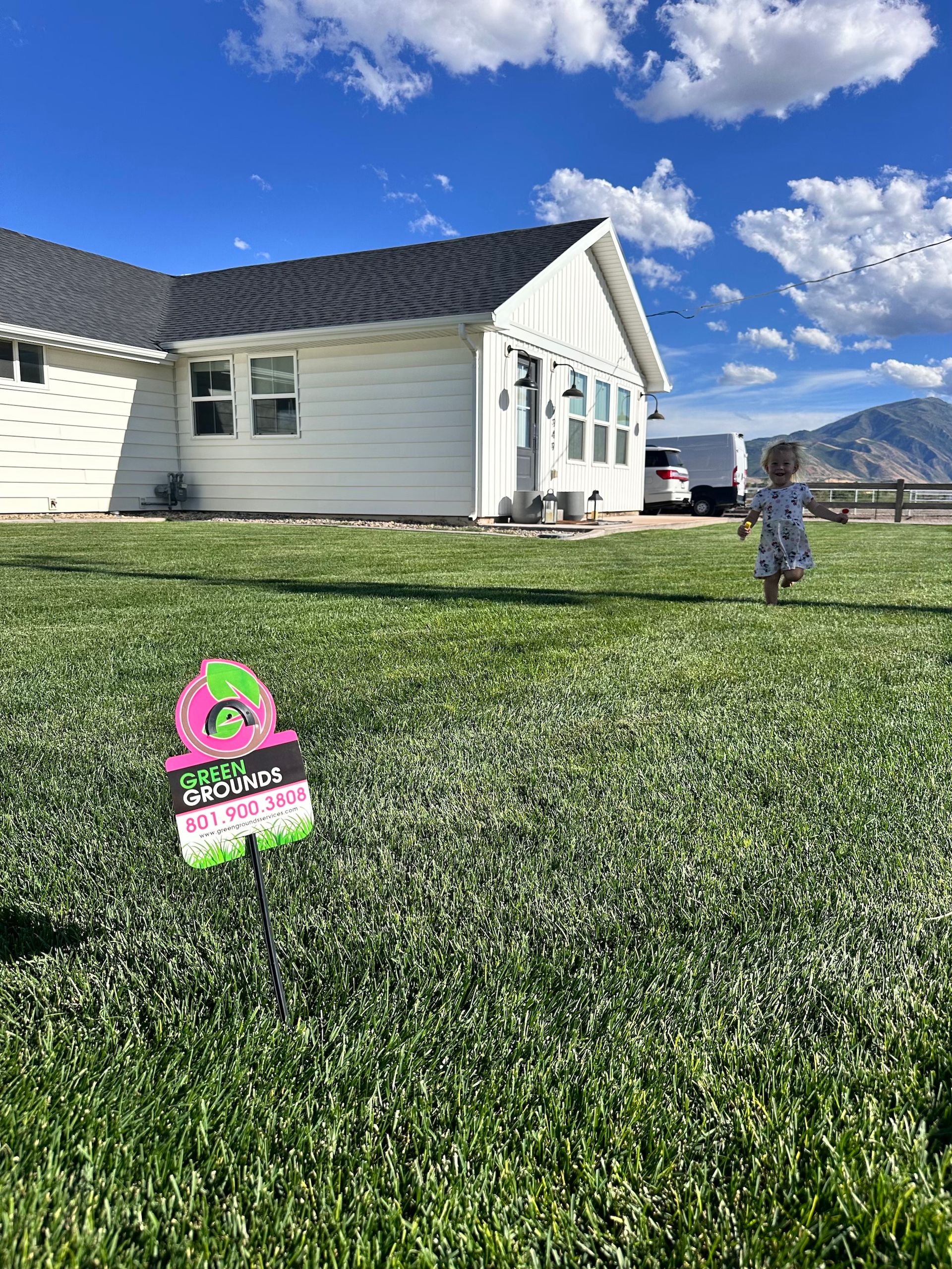 A little girl is running in front of a house with a sign in the grass.