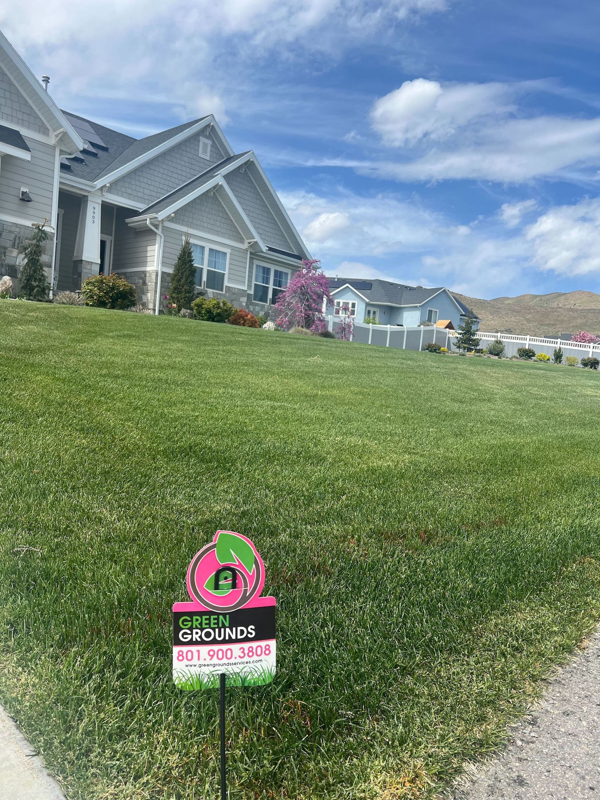 A house with a lush green lawn and a sign in front of it.