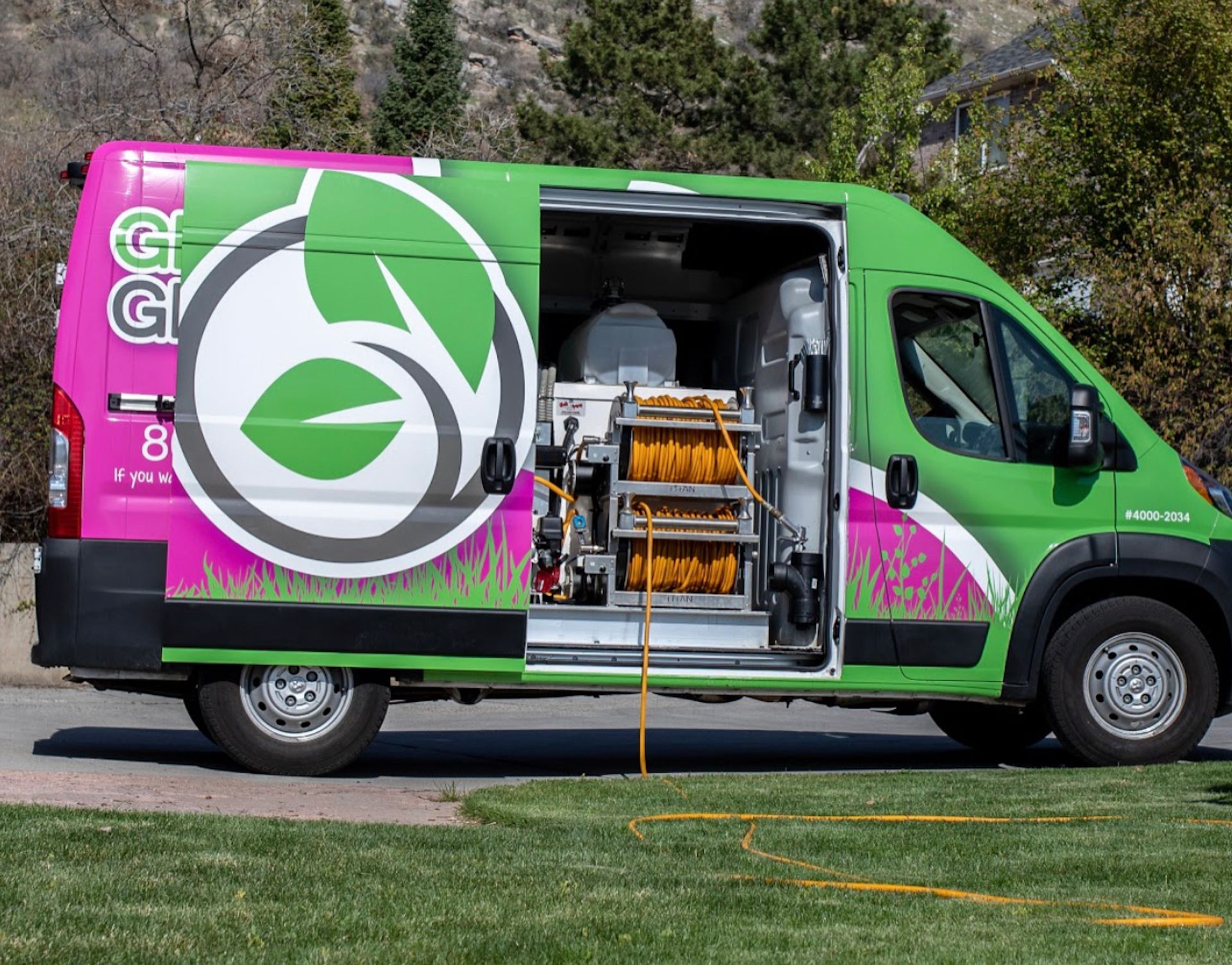 A green and pink van with the door open is parked on the side of the road.