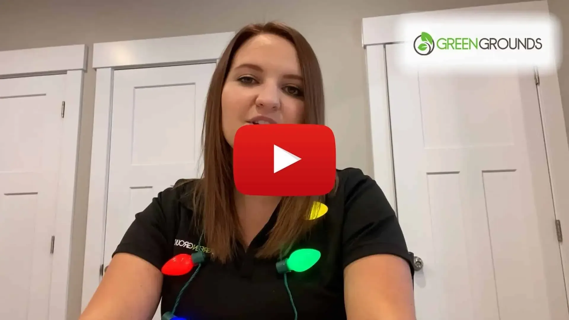 A woman is sitting at a table with christmas lights on her neck.