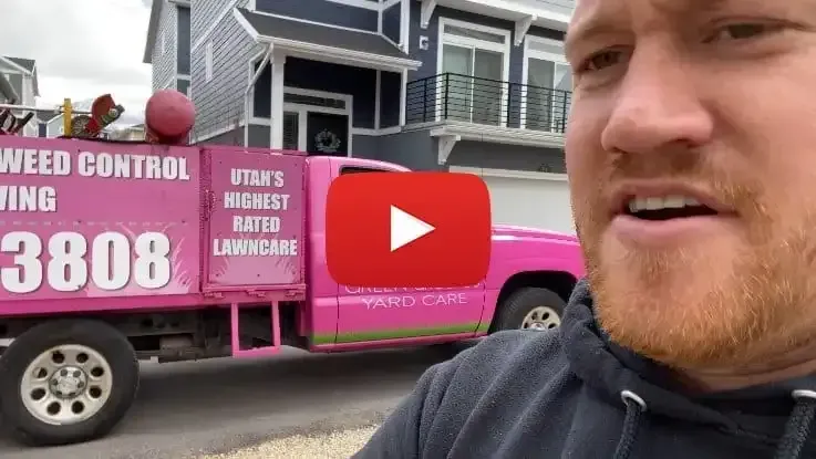 A man is standing in front of a pink weed control truck.