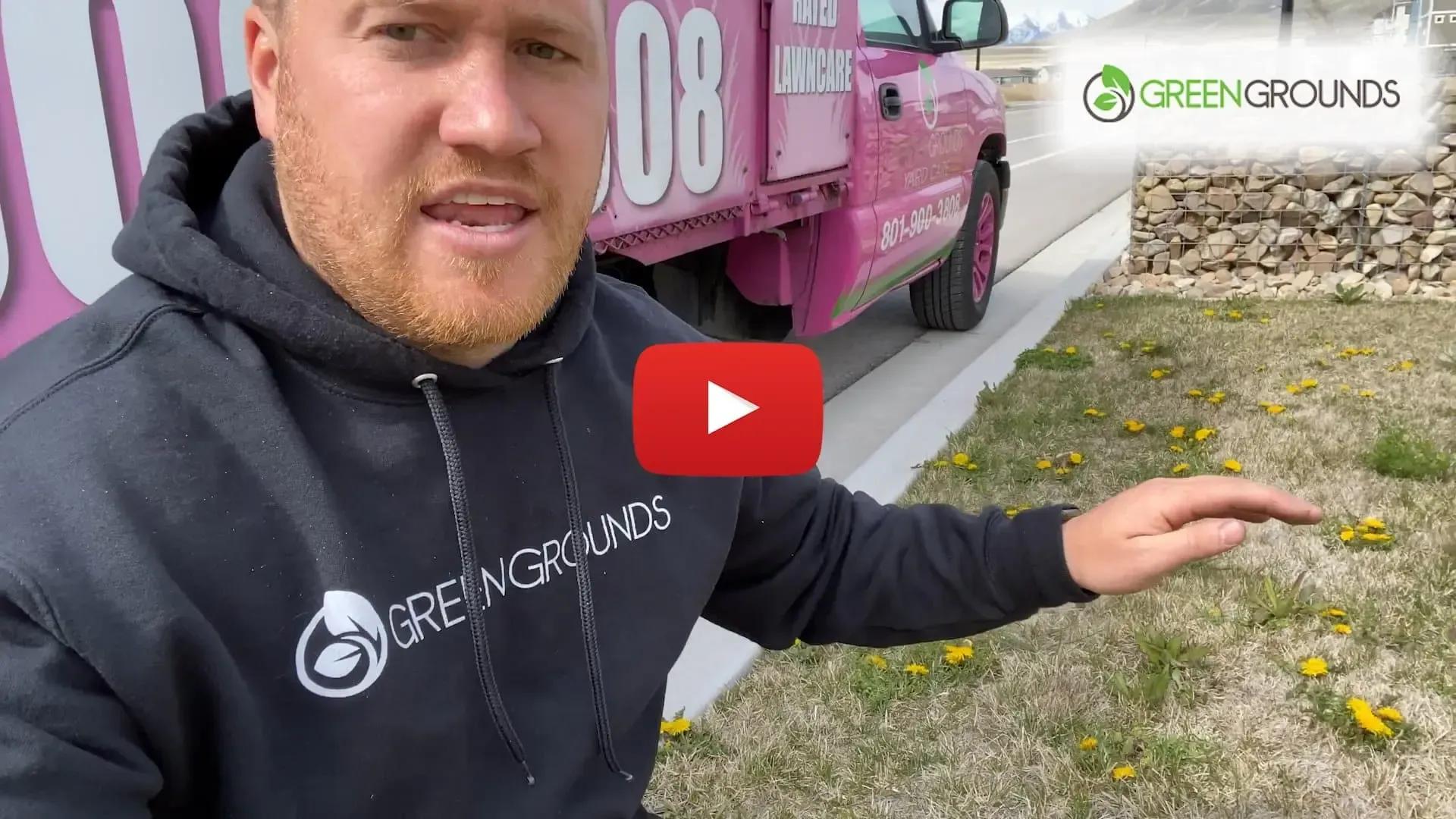 A man in a black hoodie is standing in front of a pink truck.