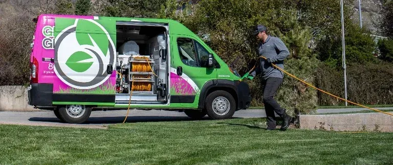 A man is standing next to a green and pink van.