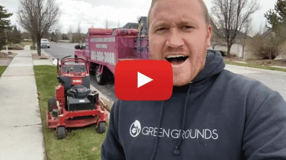 A man in a hoodie is standing in front of a lawn mower.