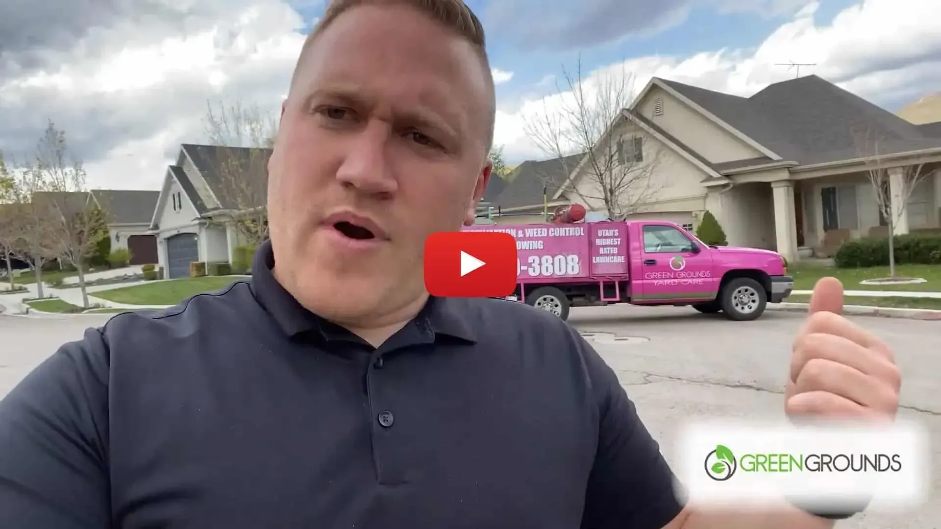 A man is standing in front of a pink truck in front of a house giving a thumbs up.