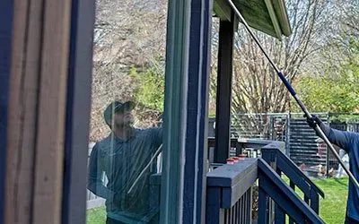 A man is cleaning a window with a long pole.