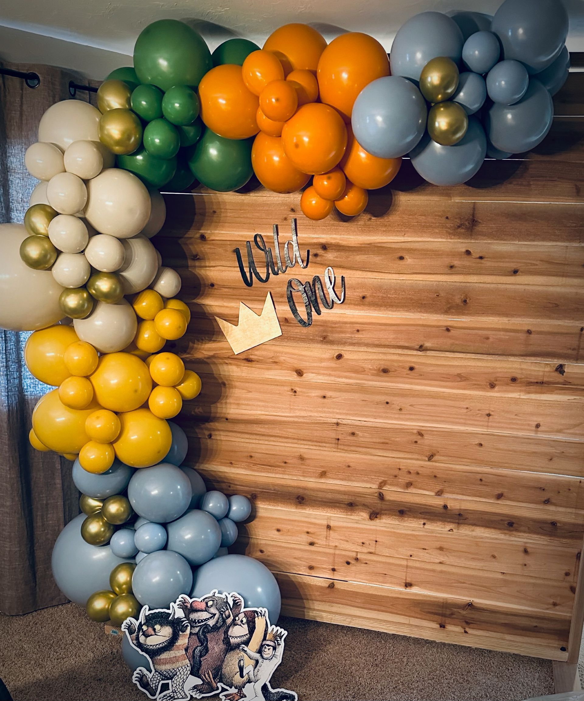 Balloon arch in earth tones against wooden backdrop;