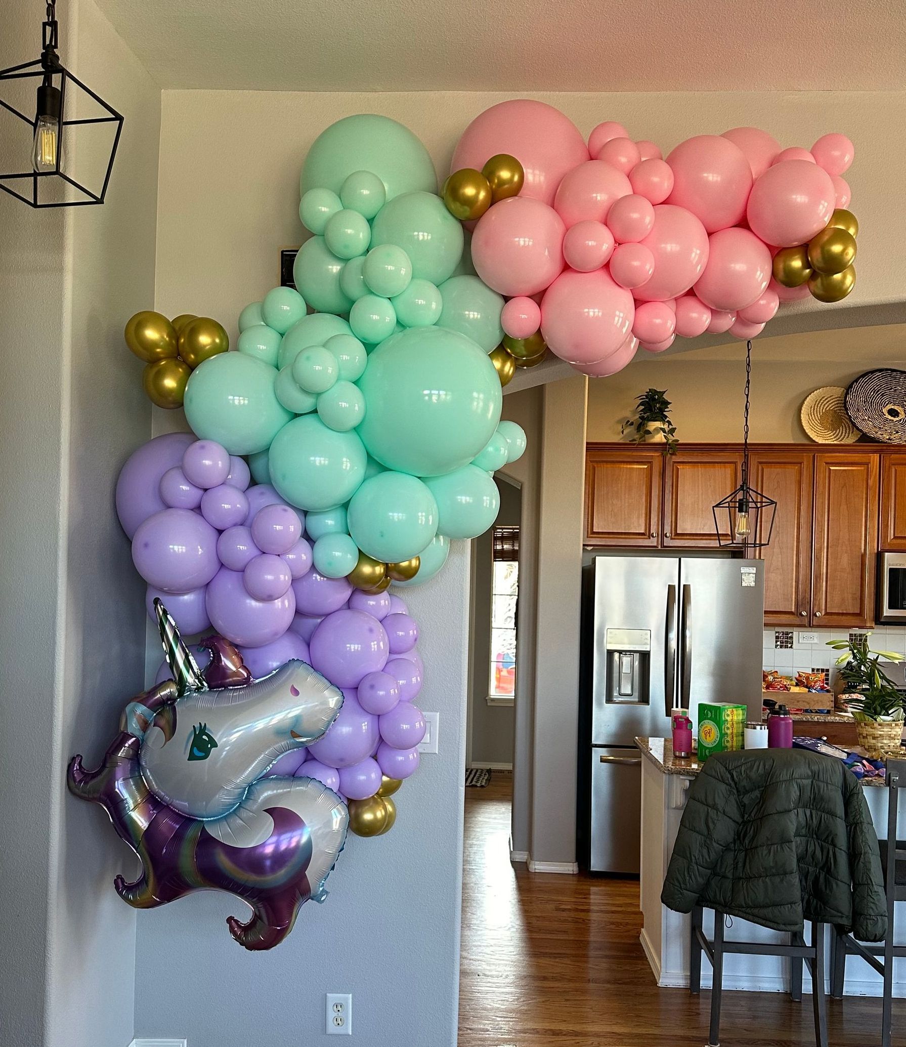 Colorful balloon arch with unicorn decoration on an interior doorway.