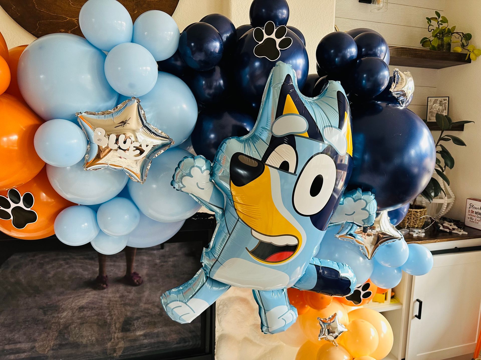 Bluey balloon with blue, orange, and navy balloons; paw prints; star balloons.
